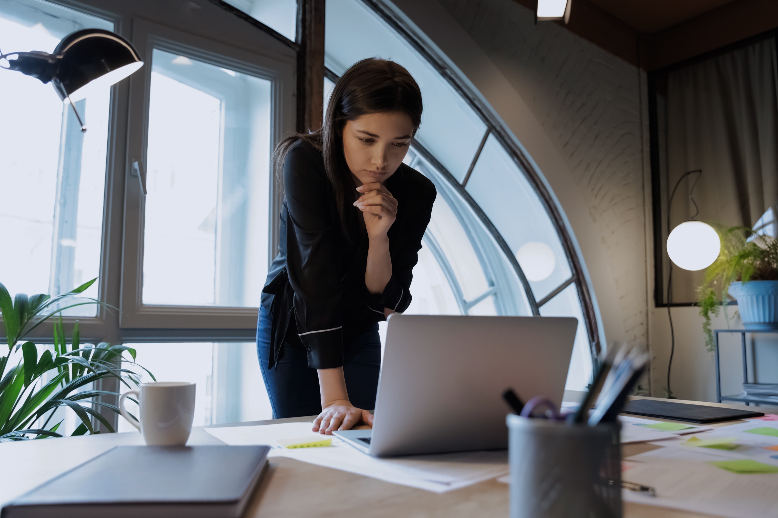 An executive pausing over a laptop, weighing an AI recommendation before committing to a decision.